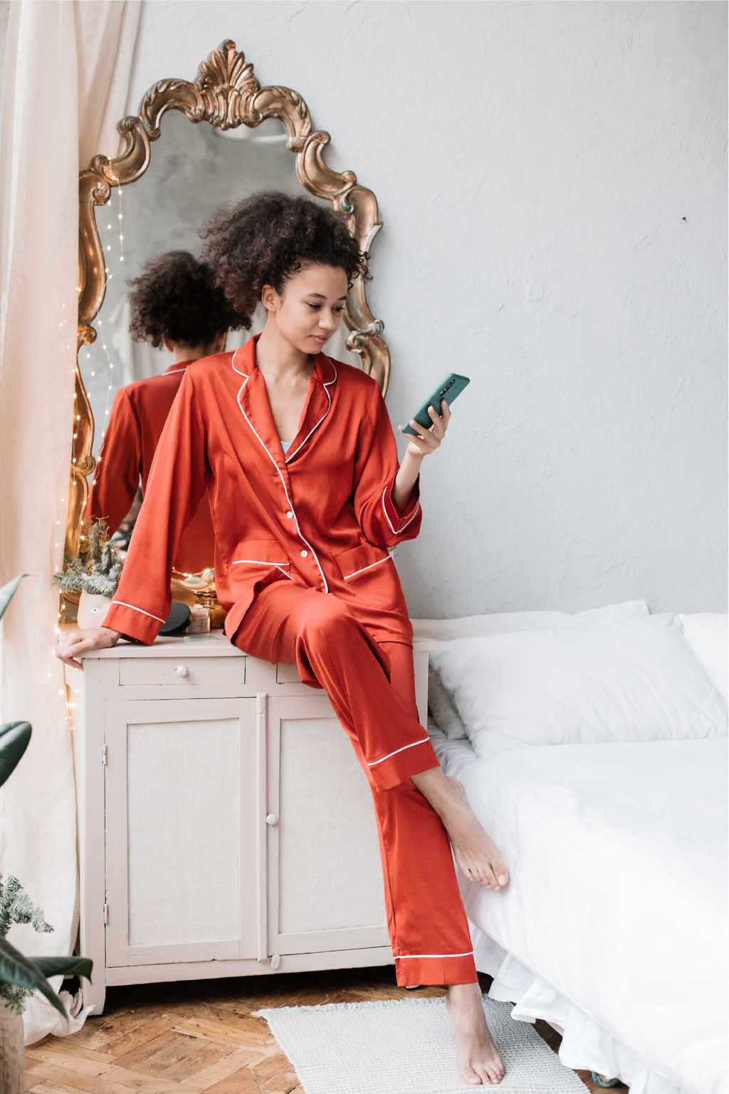 African American woman wearing pajamas while looking at her cell phone.